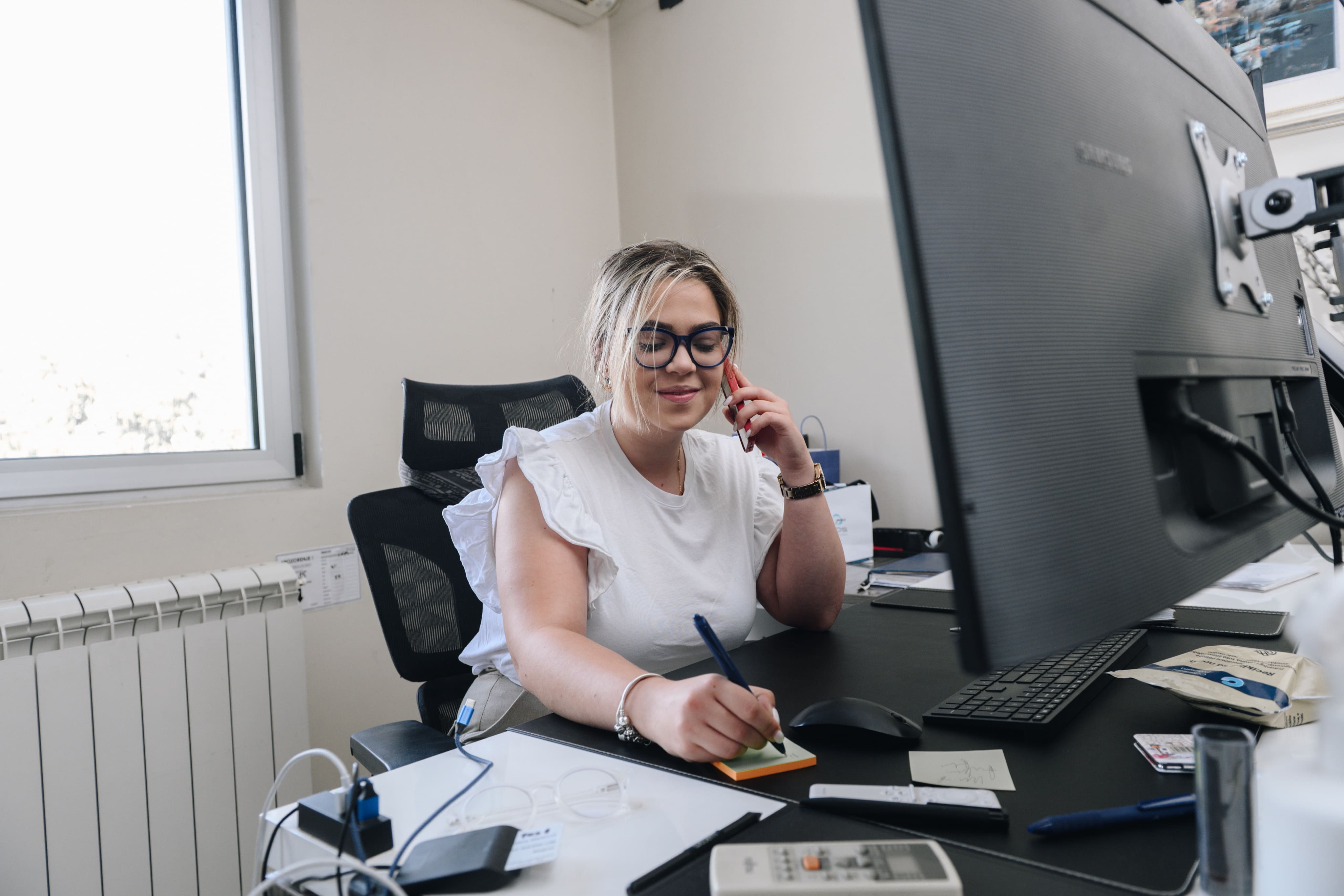 Zaposlena razgovara telefonom i zapisuje
