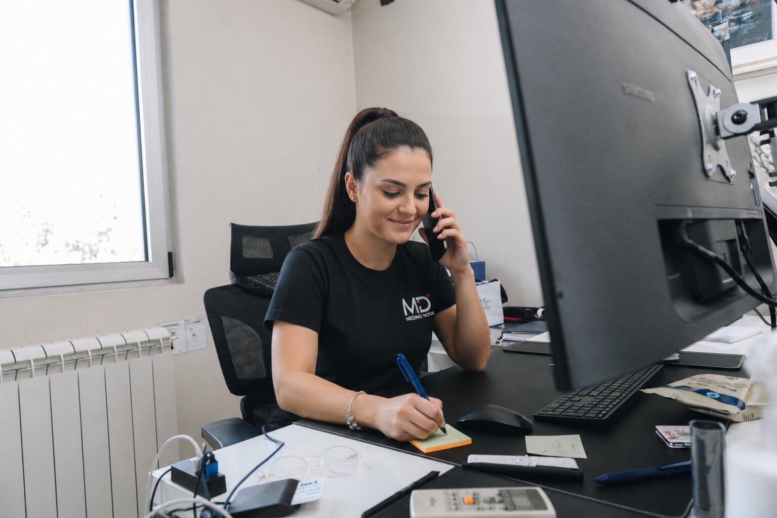 Zaposlena razgovara telefonom i zapisuje